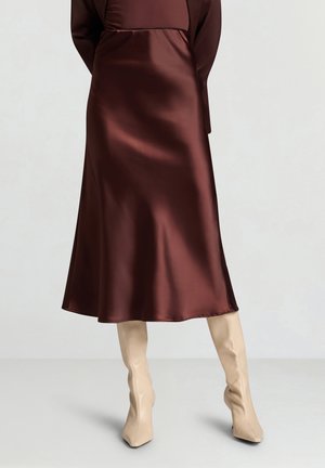 Brown satin A-line dress with a mid-length hem, soft texture, and long sleeves. Paired with beige knee-high fitted boots.