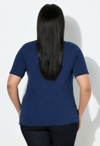 Laivastonsininen, lyhythihainen t-paita rentolla istuvuudella, valmistettu kevyestä kankaasta; takakuvassa näkyy sileä pinta ja kaareva helma.