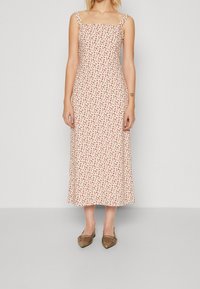Vestido midi blanco con estampado floral en rojo, escote cuadrado y tirantes finos, confeccionado en un tejido ligero con una textura suave.