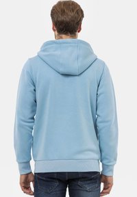 Hoodie bleu clair avec capuche à cordon, poignets et ourlet côtelés. Le tissu a l'air doux avec une texture lisse, idéal pour un style décontracté.