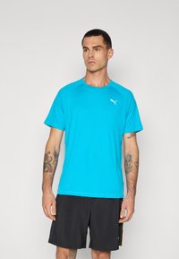 T-shirt med korte ærmer i livlig turkise farver, lavet af letvægtsmateriale. Har en rund hals og et diskret logo på brystet.