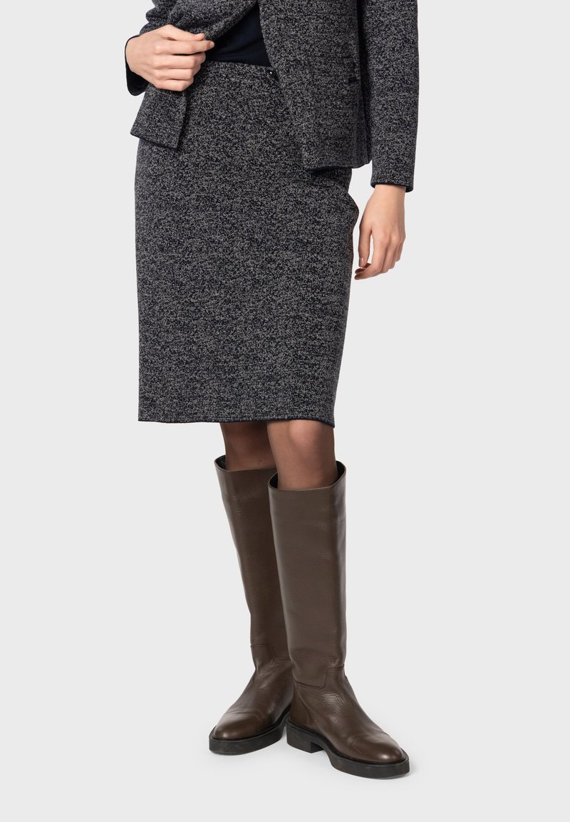 Gonna grigia scuro fino al ginocchio in tessuto testurizzato, abbinata a stivali alti in pelle marrone con finitura liscia e punta arrotondata.
