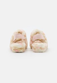 Para puszystych sandałów UGG z różowo-beżowym wzorem tie-dye, elastycznymi paskami z tyłu i grubymi, wyściełanymi podeszwami, widocznych od tyłu.