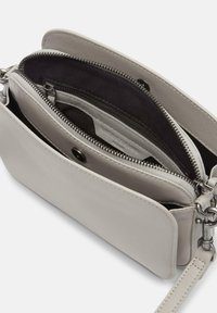 Hellgraue Leder-Crossbody-Tasche mit zwei Reißverschlussfächern, strukturiertem Oberflächenmaterial und Metallbeschlägen. Verstellbarer Riemen angebracht.