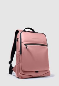 Roze rugzak met een gladde, matte afwerking, voorzien van zwarte ritssluitingen en accenten. Inclusief voorvak en gewatteerde schouderbanden voor extra comfort.