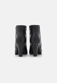 Czarne skórzane botki za kostkę o gładkiej fakturze, okrągłym nosku i 4-calowym słupkowym obcasie. Posiadają zamek błyskawiczny z tyłu dla ułatwienia zakupu.
