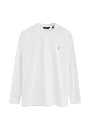 Camisa henley blanca de manga larga con tres botones y un pequeño logo de jugador de polo en azul marino en el lado izquierdo del pecho.