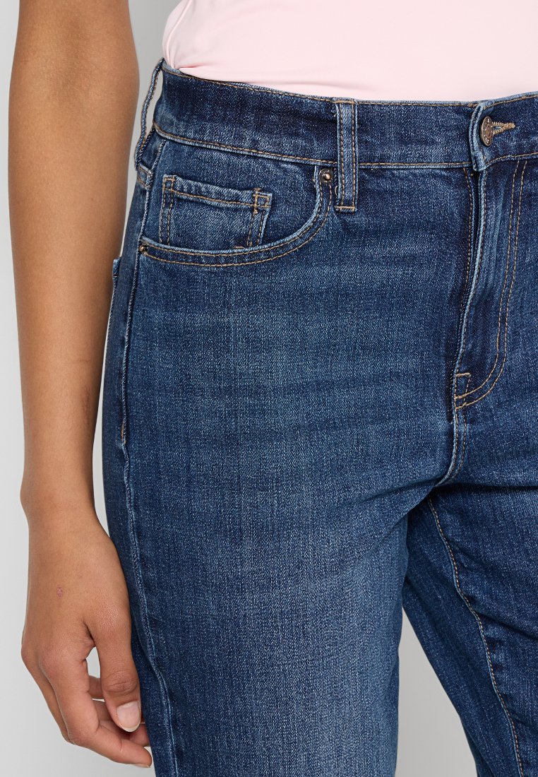 Dunkelblaue Denim-Jeans mit einer taillierten Passform, Fünf-Taschen-Design und dezenten Steppnähten. Das Material wirkt strukturiert mit einer glatten Oberfläche.