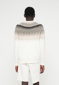 Strickpullover in Weiß, mit einem gemusterten Schulterbereich in Schwarz, Beige und Grün. Mit überschnittenen Schultern und gerippten Bündchen, strukturierte Oberfläche.