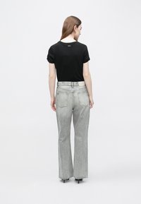 Mustad lühikeste varrukatega t-särk ja hallid laia lõikega teksad, millel on volditud varruka detail ja tavalised tagataskud. Pehme tekstuur ja lõõgastav istuvus.