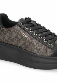 Baskets noires avec un dessus en textile brun à motifs, un design à lacets, des œillets en métal argenté et une épaisse semelle en caoutchouc noir.