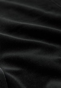 Schwarzer Samtstoff mit weicher Textur und leichtem Glanz, der subtile Wellenmuster und eine glatte Oberfläche aufweist.