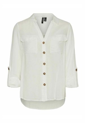 Blusa blanca de manga larga con cuello, dos bolsillos en el pecho, botones de carey en la parte delantera y en las mangas remangadas.