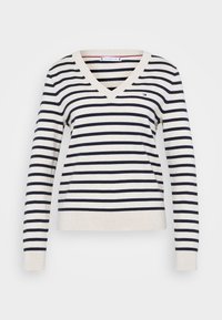 Pull à col en V rayé crème et marine à manches longues. Présente des rayures horizontales et un petit logo sur la poitrine. Texture douce.