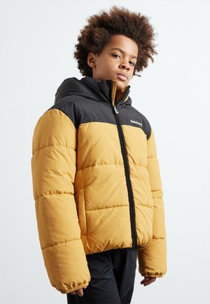 Veste doudoune jaune et noire avec une capuche, dotée d'une fermeture éclair, d'une texture matelassée et de poignets élastiques. Logo sur la poitrine.