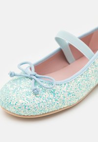 Ballet flat bleu clair pailleté avec un bout arrondi, détail en satin avec un nœud, et une sangle élastique. Doublure intérieure lisse, empeigne texturée et scintillante.