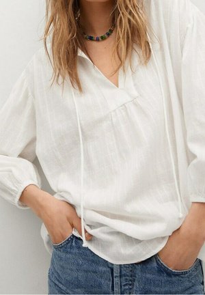 Witte blouses met lange mouwen en een V-hals, met een trekkoord, gemaakt van lichte stof. Gecombineerd met blauwe denim jeans die een relaxte pasvorm hebben.