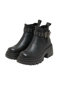 Botas de tobillo negras hechas de cuero texturizado con un tacón grueso, que presentan ojales metálicos y un detalle de correa con hebilla.