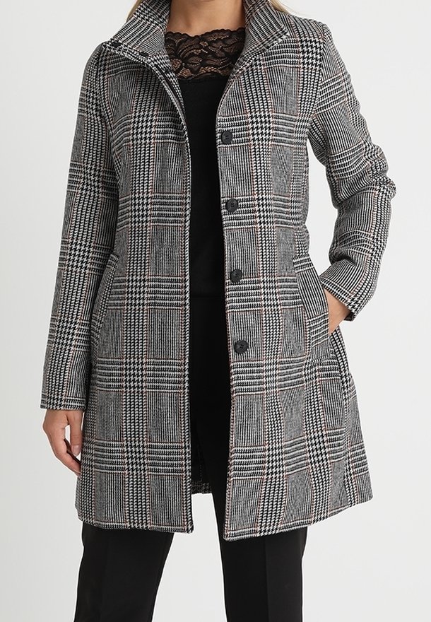 Cappotto scozzese in bianco e nero con sottili accenti rossi, dotato di colletto a scollo, bottoni frontali e tasche laterali. Finitura in tessuto textured.