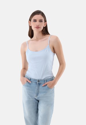 Helles blaues Top mit dünnen Trägern, kombiniert mit lockeren, hellen Jeans aus Denim, die eine hohe Taille und seitliche Taschen haben.