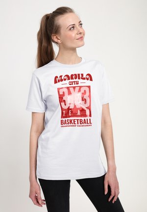 Kvinde med hestehale iført hvid t-shirt med rød tekst "Manila City 3x3 Team Basketball Championship Tournament" og basketballkurv-grafik.