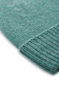 Maglione lavorato a maglia turchese, con primo piano che mostra una texture morbida, polsini a costine e un aspetto leggero e accogliente.