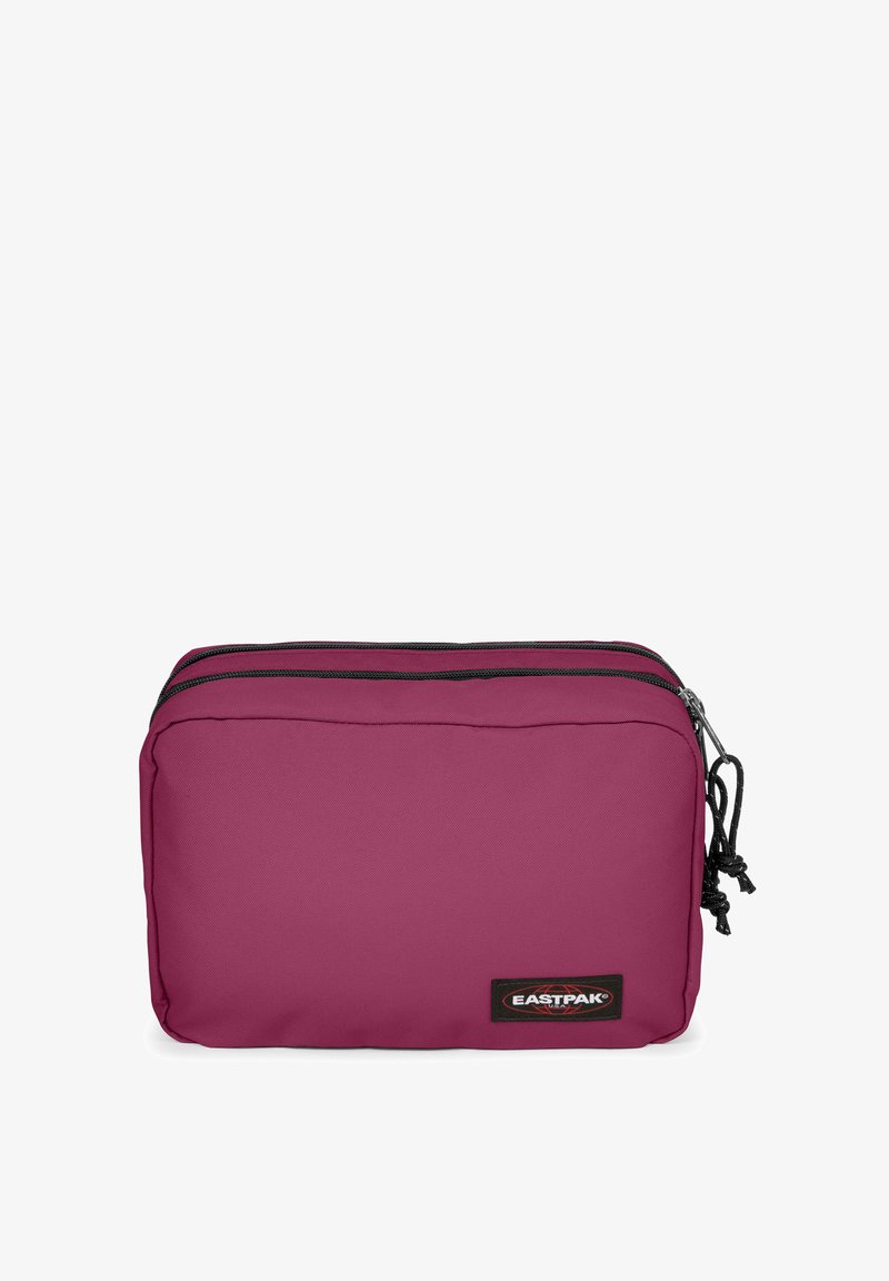 Sac Eastpak, forme rectangulaire, en tissu durable, de couleur violet foncé. Présente deux fermetures éclair noires et un écusson logo sur un côté.