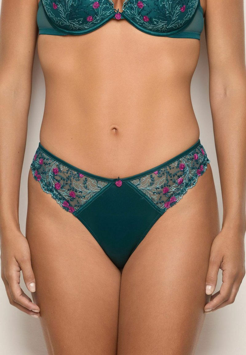 String en dentelle teal avec broderies florales en rose et vert. Il possède des panneaux latéraux transparents et une partie frontale lisse, agrémentée de petits accents.