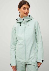 Giubbotto impermeabile verde menta chiaro con cappuccio regolabile, cerniera frontale e tasche. Presenta polsini elastici e una texture morbida.