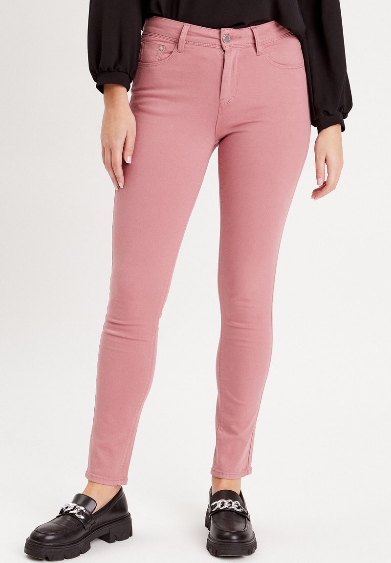 Jeans skinny roses en tissu doux en mélange de coton, avec un design classique à cinq poches et des détails de couture subtils.