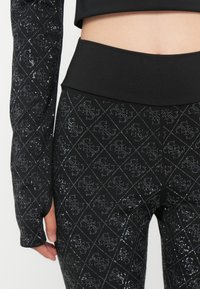 Top sportivo nero e leggings con un motivo a diamond e dettagli in glitter. I leggings hanno una vita alta e maniche lunghe.
