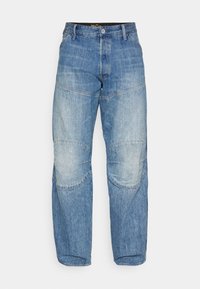 Helleblaue Denim-Jeans mit lockerer Passform, die über Faltennähte und ausgewaschene Bereiche verfügen. Der Bund hat einen Knopfverschluss und Gürtelschlaufen.