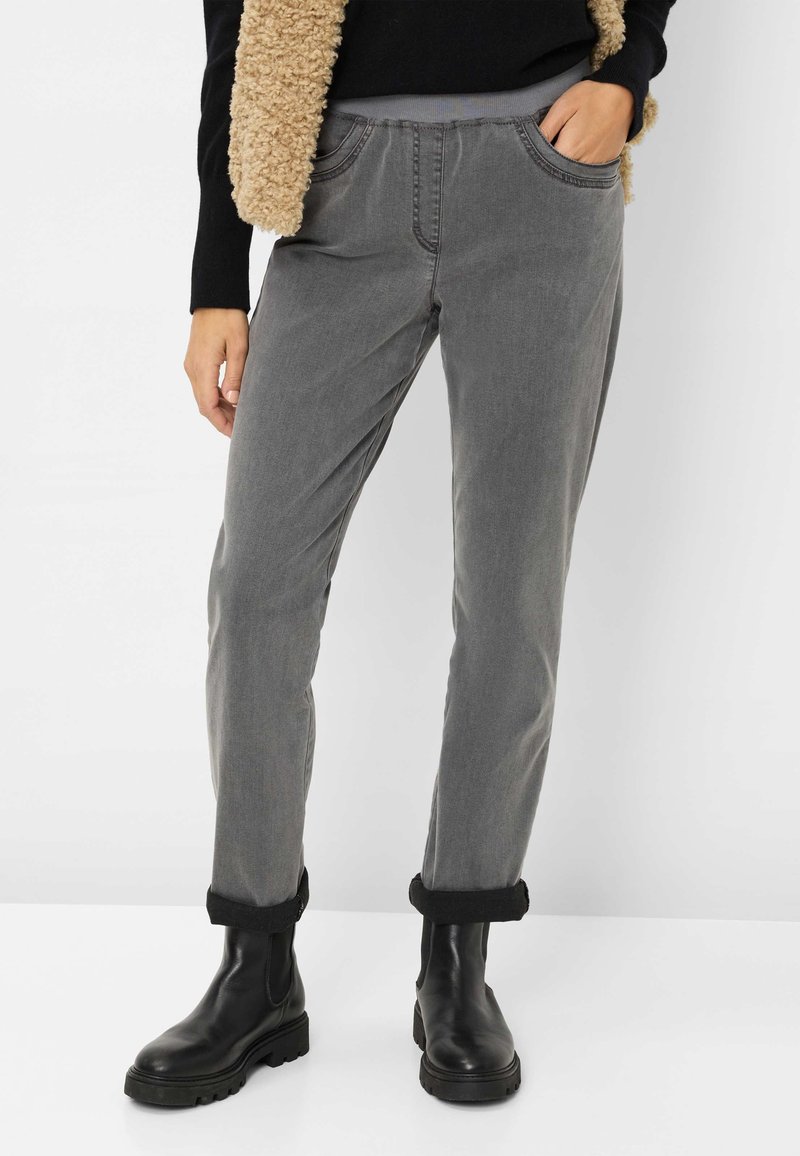 Pantaloni grigi a gamba dritta con tasche laterali, orli risvoltati e una texture morbida, abbinati a stivaletti neri alla caviglia.