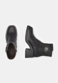 Black leather ankle boots with a square toe, chunky heel, and silver buckle detail. The sole features a textured grip pattern.