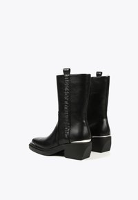Black leather ankle boots with a square toe, side pull tabs, embossed brand logo, and a block heel with silver accents.