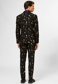 Black suit featuring a gold festive print with stars, champagne glasses, and party items. Tailored fit with matching trousers.