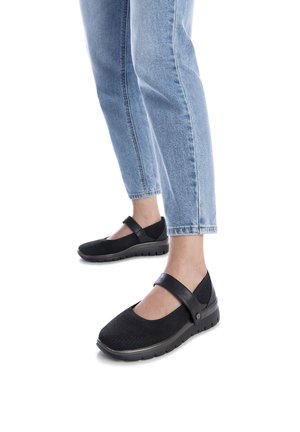 Zapatos Mary Jane negros con parte superior texturizada, correa ajustable y suela acolchada, combinados con jeans de mezclilla azul claro.