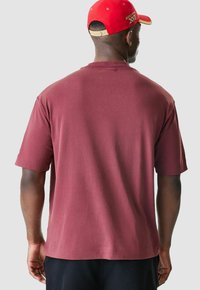 Burgunderfarbendes T-Shirt mit kurzen Ärmeln und lässigem Sitz, hergestellt aus Baumwolle, mit einem klassischen Rundhalsausschnitt und glatter Textur.