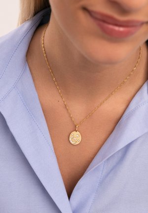 Collar de oro con una cadena retorcida y un colgante redondo que presenta una letra acentuada con diamantes y motivos de estrellas sobre un fondo texturizado.