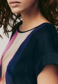 Kortärmad topp med en blandning av färger—rosa, mörkblå och svart. Slät textur med rund halsringning och en lätt genomskinlig panel.