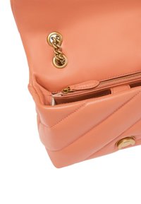 Bolso de piel de melocotón con diseño acolchado, hardware de cadena dorada y cierre de cremallera. Cuenta con un detalle del logo en la parte frontal.