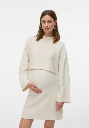 Abito premaman a coste color crema con collo alto e maniche a campana lunghe, caratterizzato da un design con top corto e una texture liscia.
