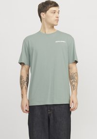 Lichtgroene katoenen T-shirt met een ronde hals en korte mouwen, voorzien van een kleine logoprint in het wit op de bovenste linkerkant van de borst.