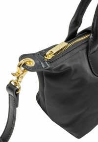 Czarna syntetyczna torebka o teksturowanym wykończeniu, z zlotym zamkiem błyskawicznym, złotymi okuciami i regulowanym paskiem. Kompaktowy i zorganizowany kształt.