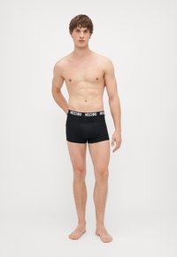 Čierne boxerky s čierno-bielym značkovým pásom, s tesným strihom a hladkým materiálom z bavlnenej zmesi.