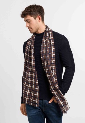 Brown patterned scarf made of lightweight fabric, featuring a geometric design with cream and navy accents, draped around a model’s neck.