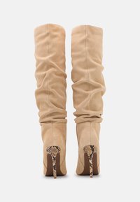 Bottes beiges de style décontracté montantes en su ède, avec une finition texturée et un détail de talon en motif serpent.