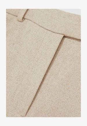 Beige linnedragtbukser, der viser et struktureret stof med en fold på den ene side, med en elastisk talje og uden synligt hardware.