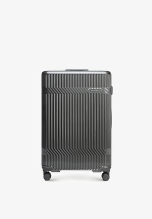 Valise rigide gris foncé avec des rainures verticales, quatre roues multidirectionnelles et une poignée supérieure, marquée "Wittchen" à l'avant.