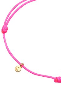 Justerbart armband med ett klart rosa nylonband och en guldtonad metalltagg inskriven med "A9 925" nära en dekorativ knut.